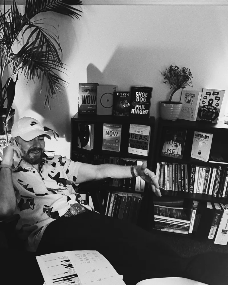 Guy Muller on a phone call at his desk, working through a redacted document, with shelves of publishing and intellectual property law books behind him